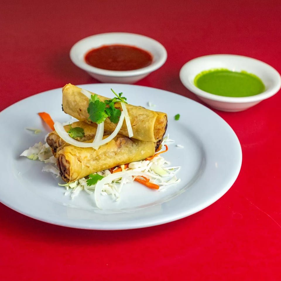 Crispy Indian spring rolls with shredded cabbage, carrots, onions, and cilantro, served with two dipping sauces.